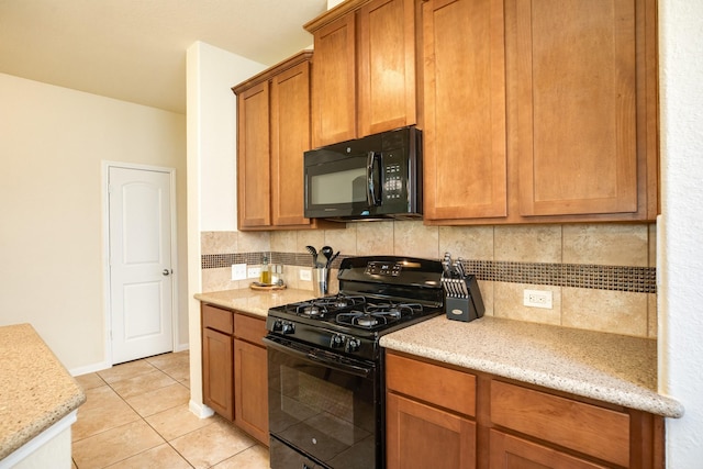 kitchen featuring light stone counters, light tile patterned floors, decorative backsplash, and black appliances