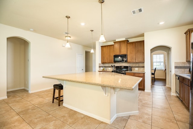 kitchen with pendant lighting, black appliances, a kitchen breakfast bar, and a center island