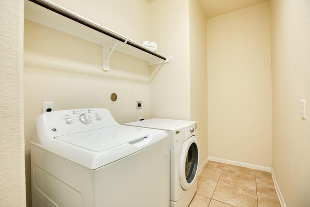 laundry room with washing machine and dryer and light tile patterned floors