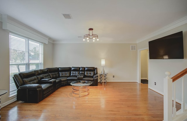 living room with ornamental molding, a chandelier, and light hardwood / wood-style floors