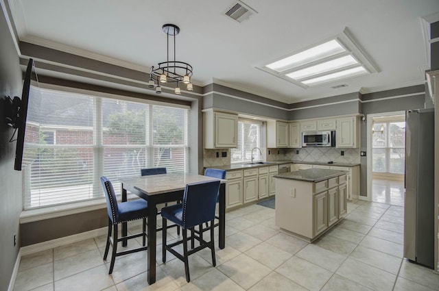 kitchen featuring sink, hanging light fixtures, a center island, cream cabinets, and ornamental molding