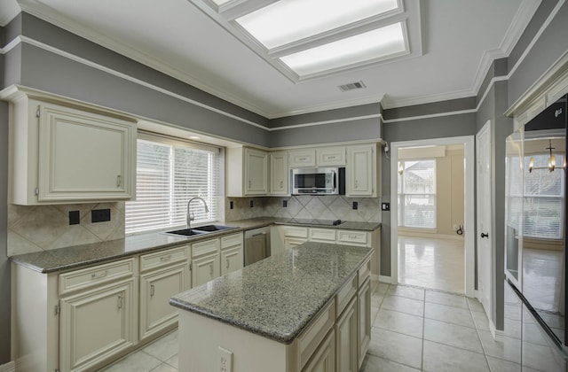 kitchen featuring appliances with stainless steel finishes, sink, a kitchen island, and cream cabinetry