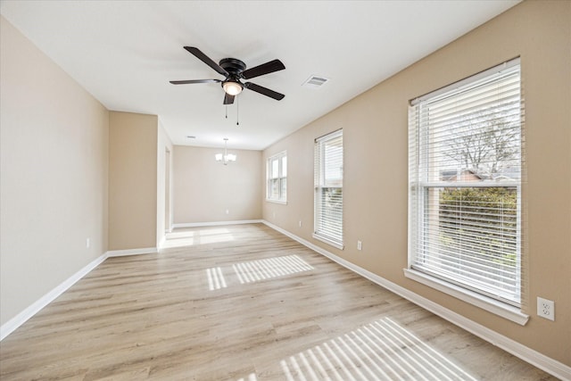 unfurnished room featuring ceiling fan with notable chandelier and light hardwood / wood-style floors