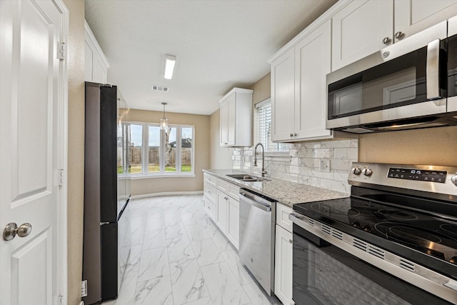 kitchen featuring sink, white cabinets, backsplash, stainless steel appliances, and light stone countertops