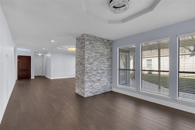 unfurnished room featuring dark hardwood / wood-style flooring, a raised ceiling, and a textured ceiling