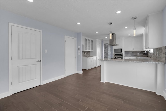 kitchen with sink, hanging light fixtures, island range hood, white cabinets, and oven