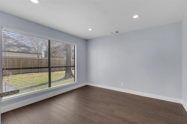 spare room featuring dark wood-type flooring and a textured ceiling