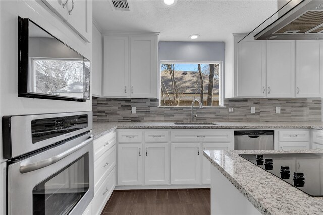 kitchen with sink, white cabinets, light stone counters, stainless steel appliances, and custom range hood