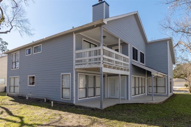 rear view of house with a balcony, a yard, and a patio area