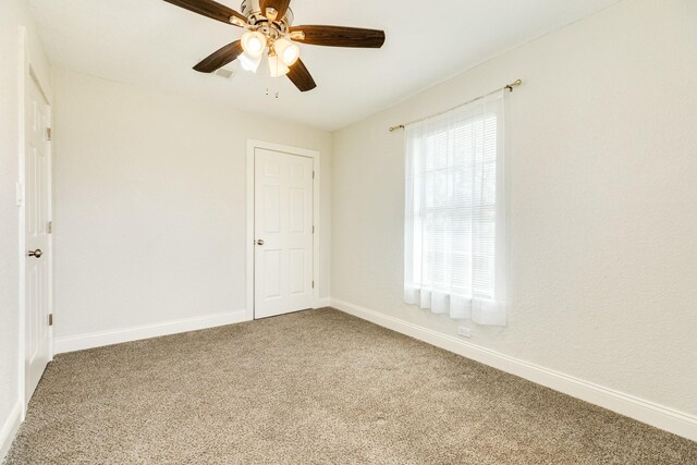 carpeted spare room featuring ceiling fan