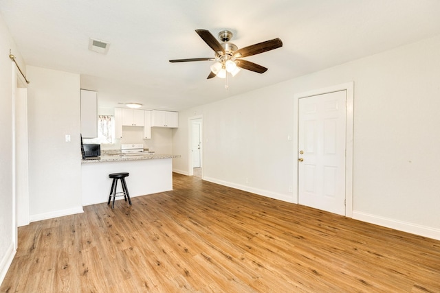 unfurnished living room featuring ceiling fan and light hardwood / wood-style floors