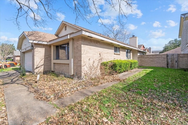 view of side of property featuring a garage and a lawn