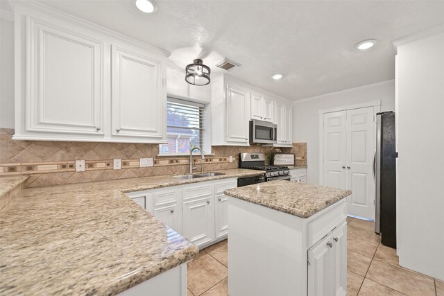 kitchen featuring sink, white cabinets, a center island, stainless steel appliances, and light stone countertops