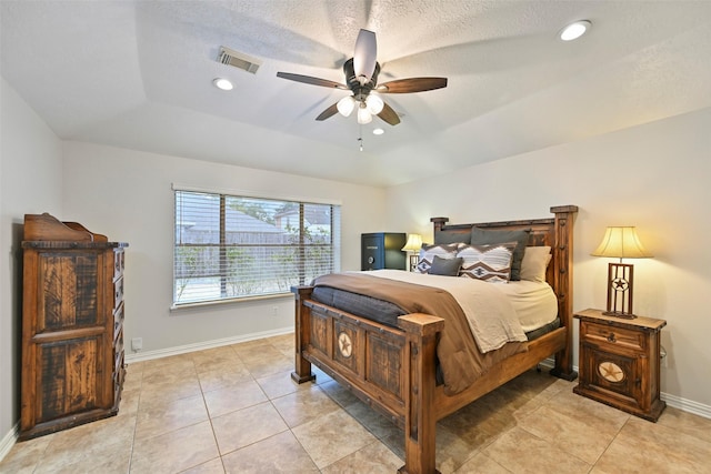 tiled bedroom featuring a raised ceiling, a textured ceiling, and ceiling fan