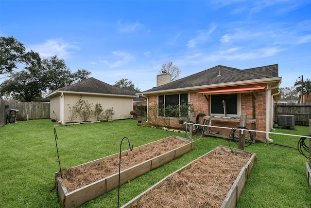 rear view of property with brick siding, a chimney, a fenced backyard, a yard, and a garden