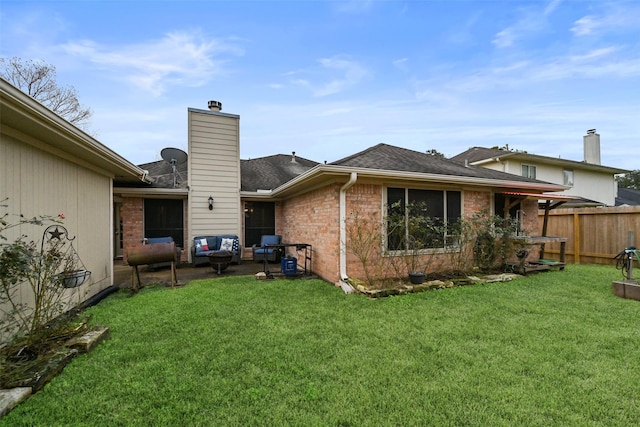 rear view of property featuring a lawn, fence, brick siding, a chimney, and a patio area