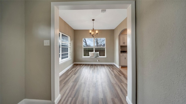 unfurnished dining area featuring hardwood / wood-style flooring and a notable chandelier