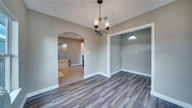 empty room featuring hardwood / wood-style flooring and a chandelier