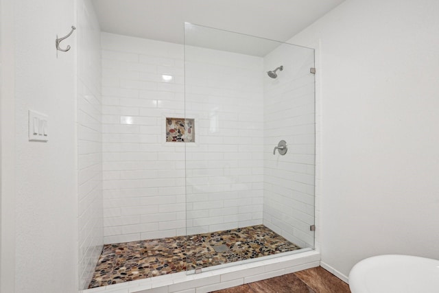 bathroom with hardwood / wood-style flooring and shower with separate bathtub