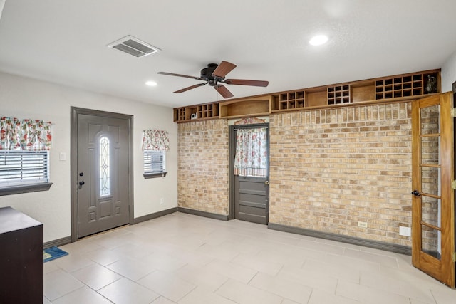 entryway featuring ceiling fan and brick wall