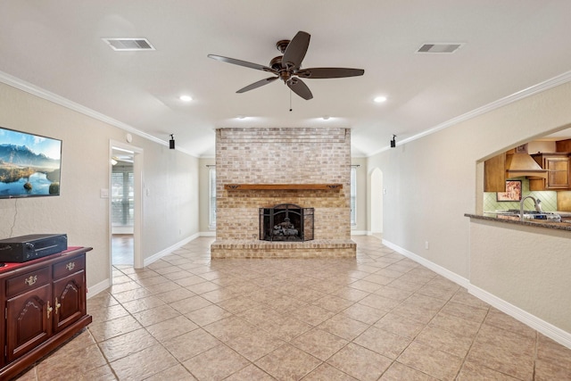 tiled living room with crown molding, sink, ceiling fan, and a fireplace