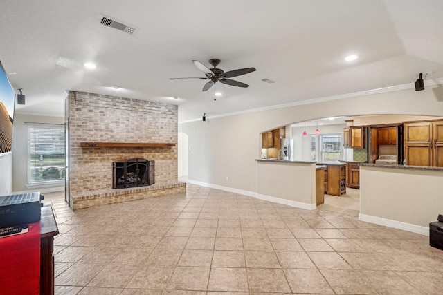 tiled living room with crown molding, ceiling fan, vaulted ceiling, and a brick fireplace