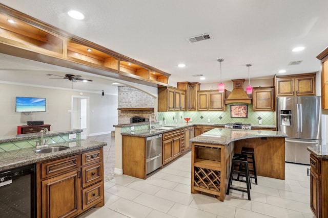 kitchen featuring decorative light fixtures, dishwasher, sink, a center island, and stainless steel fridge with ice dispenser