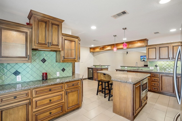 kitchen with a breakfast bar, sink, a center island, hanging light fixtures, and stainless steel appliances