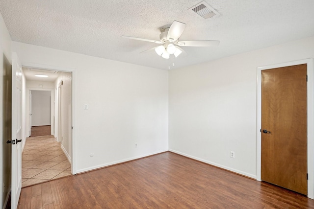 empty room with ceiling fan, wood-type flooring, and a textured ceiling