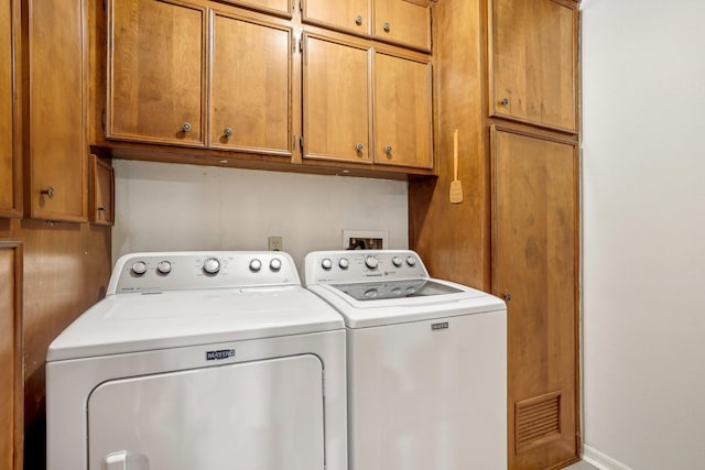 clothes washing area featuring cabinets and washer and clothes dryer