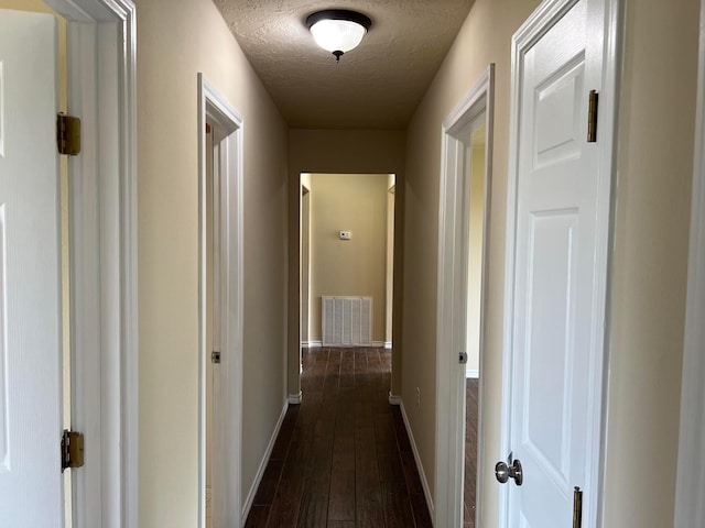 corridor featuring dark hardwood / wood-style floors and a textured ceiling