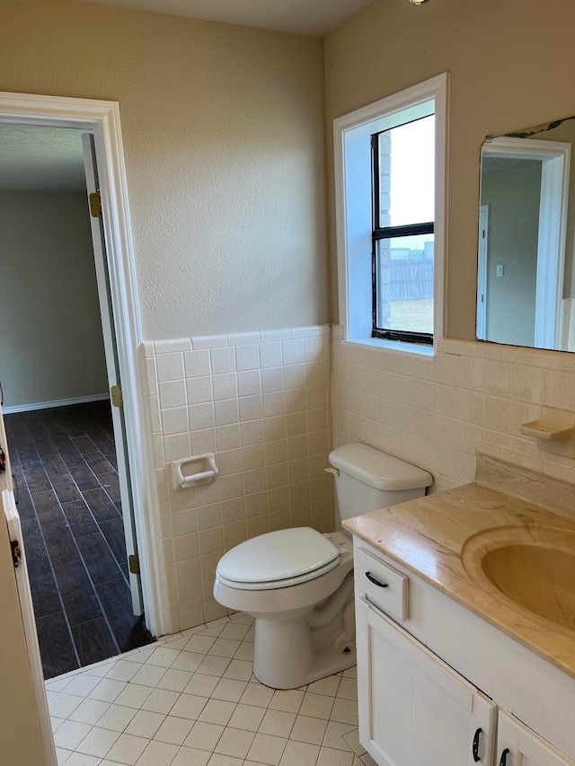 bathroom featuring vanity, toilet, tile patterned flooring, and tile walls