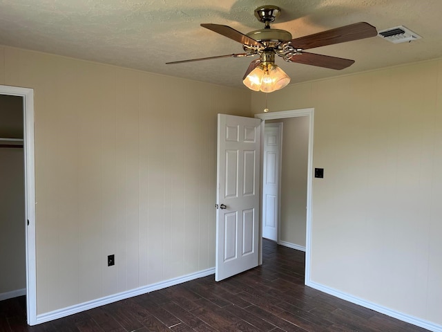 unfurnished bedroom featuring ceiling fan, dark hardwood / wood-style floors, and a textured ceiling