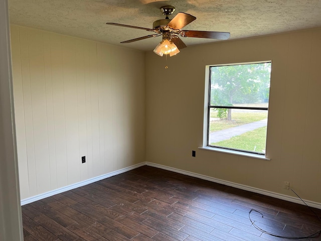 empty room with ceiling fan, dark hardwood / wood-style floors, and a textured ceiling