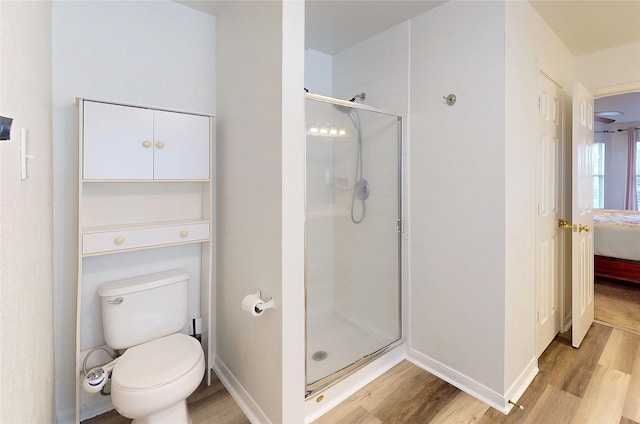 bathroom featuring hardwood / wood-style floors, a shower with shower door, and toilet