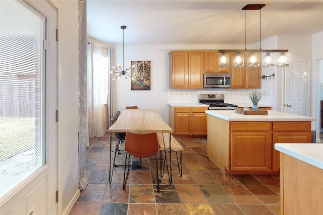 kitchen with hanging light fixtures, a wealth of natural light, a kitchen island, and appliances with stainless steel finishes