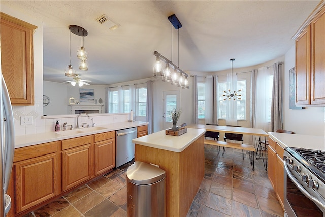 kitchen with a kitchen island, appliances with stainless steel finishes, sink, and hanging light fixtures