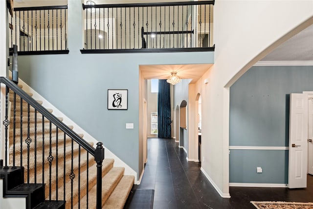 stairway featuring a high ceiling, ornamental molding, and a notable chandelier