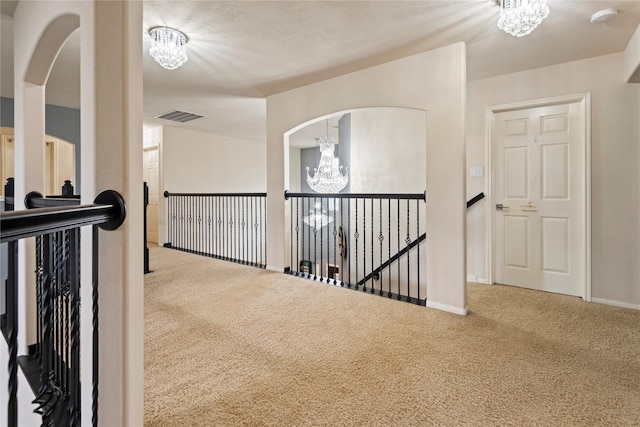 hall featuring an inviting chandelier and carpet