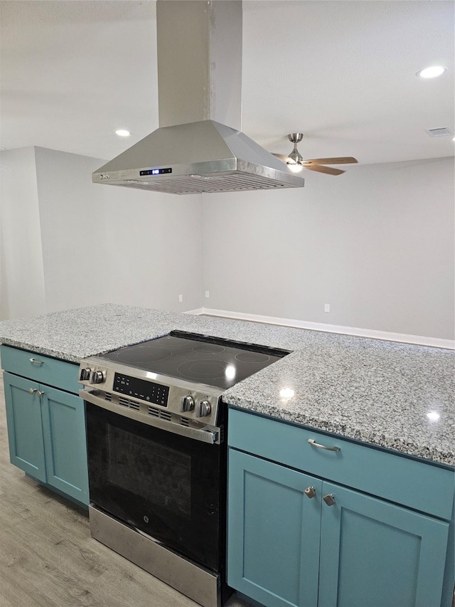 kitchen with light stone counters, stainless steel electric range oven, light hardwood / wood-style flooring, and island range hood