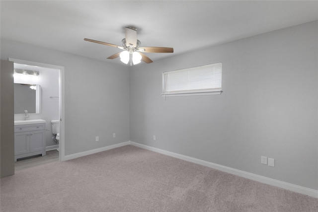 unfurnished bedroom with ceiling fan, ensuite bathroom, sink, and light carpet