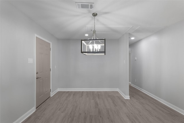 unfurnished dining area with a chandelier and light hardwood / wood-style flooring