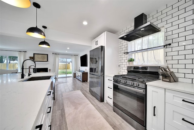 5307 Alba Rd, Houston, TX 77091 - kitchen with stainless steel gas range, freestanding refrigerator, wall chimney range hood, a sink, and open floor plan