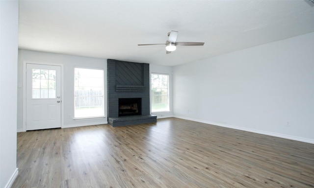 unfurnished living room featuring a brick fireplace, ceiling fan, and light hardwood / wood-style flooring