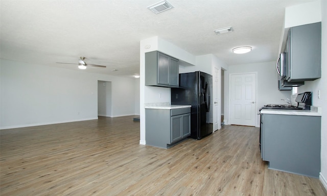 kitchen with black fridge with ice dispenser, a textured ceiling, light wood-type flooring, gray cabinets, and ceiling fan