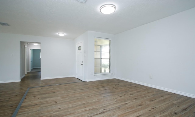 empty room with dark hardwood / wood-style flooring and a textured ceiling