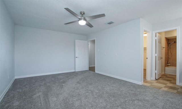 unfurnished bedroom with ceiling fan, connected bathroom, light carpet, and a textured ceiling