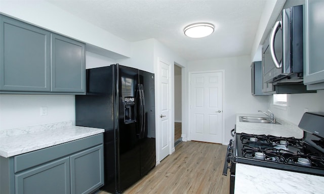 kitchen featuring gray cabinetry, sink, black appliances, and light wood-type flooring