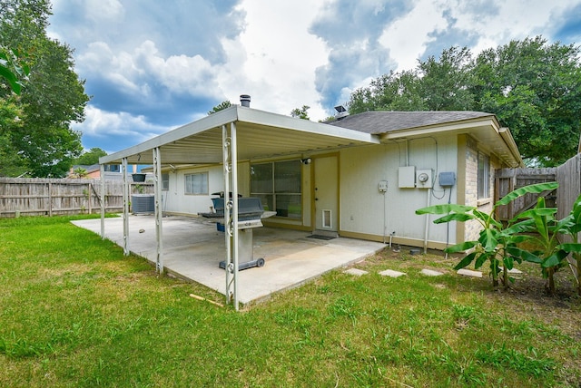 rear view of property with cooling unit, a lawn, and a patio area