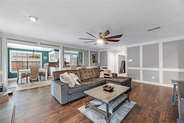 living room featuring ceiling fan, ornamental molding, dark hardwood / wood-style floors, and a textured ceiling